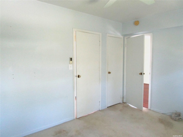 unfurnished bedroom with ceiling fan, light carpet, and a closet