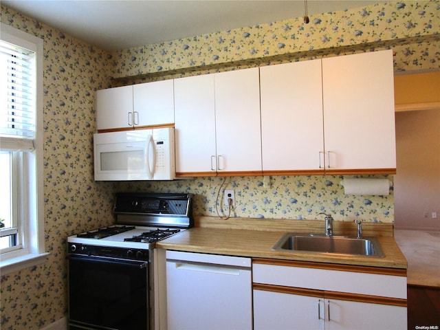 kitchen with white appliances, white cabinetry, and sink