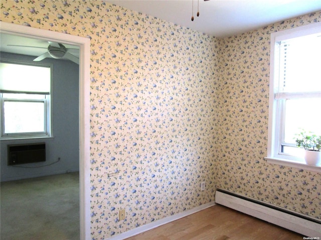 empty room with wood-type flooring, baseboard heating, a wealth of natural light, and a wall mounted AC