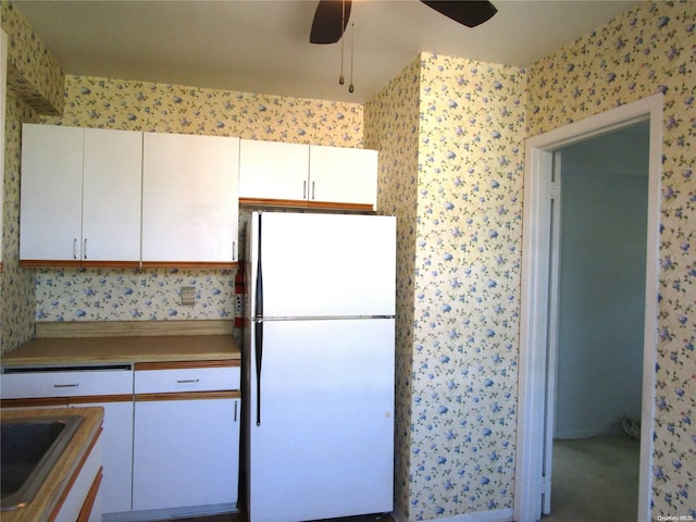 kitchen featuring ceiling fan, sink, white cabinets, and white refrigerator