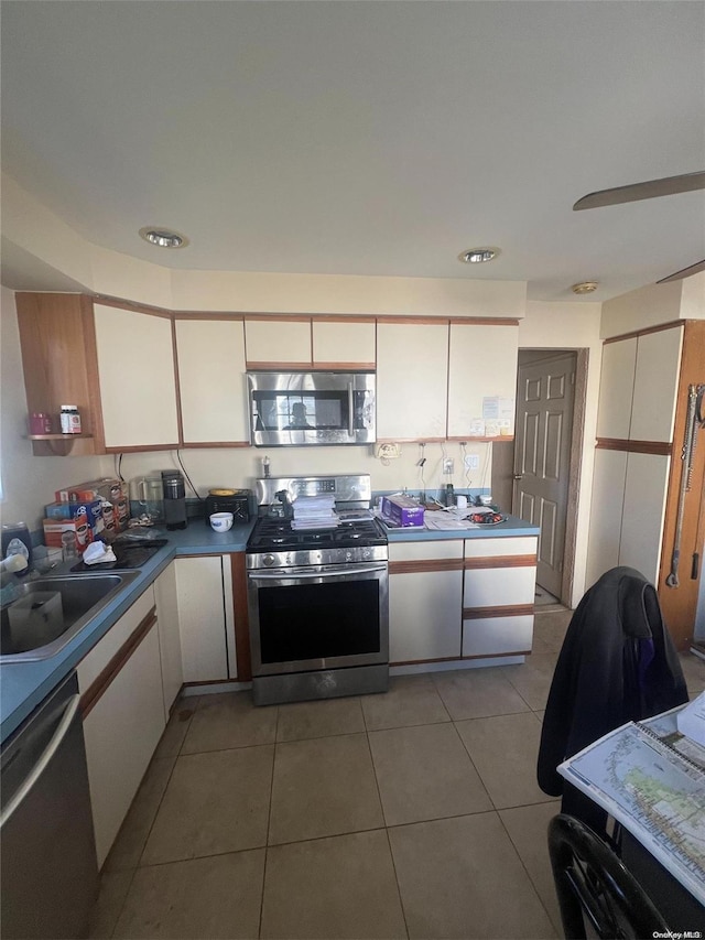 kitchen with white cabinets, light tile patterned floors, sink, and appliances with stainless steel finishes