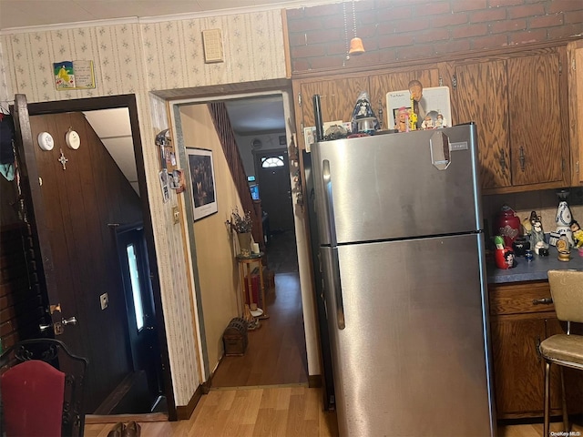 kitchen featuring stainless steel refrigerator, crown molding, and light hardwood / wood-style floors