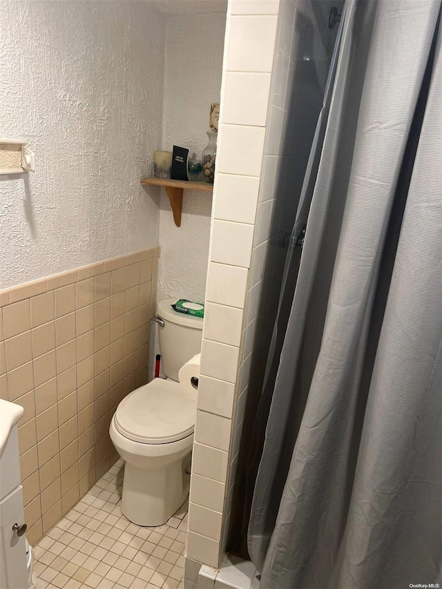 bathroom with tile patterned floors, tile walls, and toilet