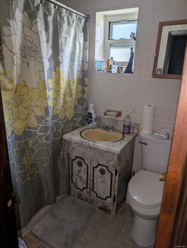 bathroom featuring tile patterned floors, toilet, sink, tile walls, and decorative backsplash