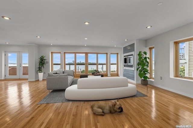 living room with a water view, french doors, and light hardwood / wood-style flooring