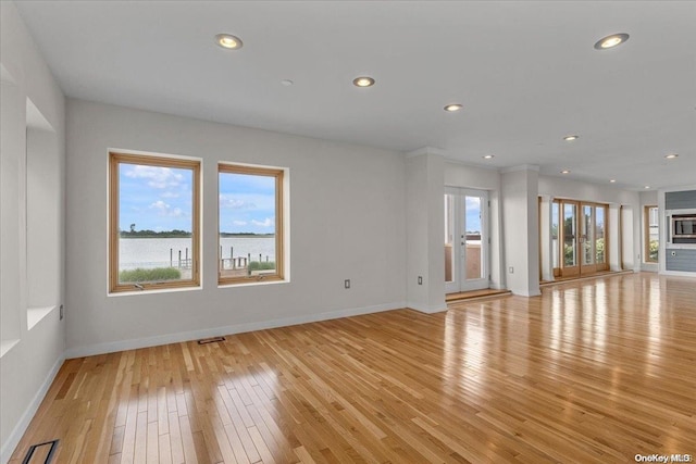 unfurnished living room with light hardwood / wood-style floors and a water view