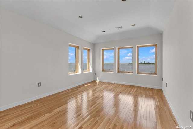 unfurnished room featuring light hardwood / wood-style floors and vaulted ceiling