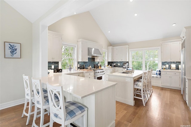 kitchen featuring a kitchen bar, white cabinetry, a kitchen island, and ventilation hood