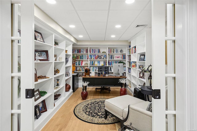 office area with hardwood / wood-style flooring, a paneled ceiling, and built in shelves