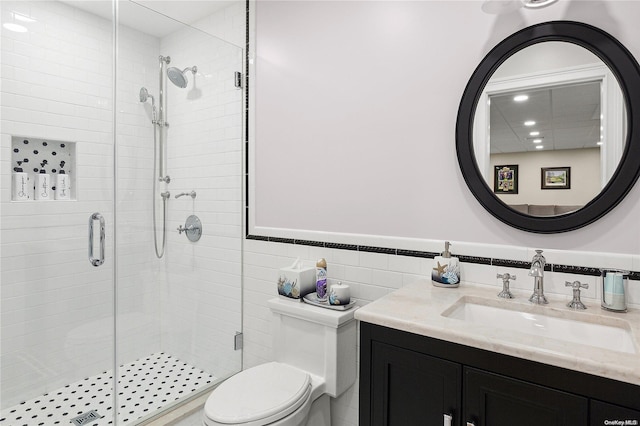 bathroom featuring walk in shower, vanity, tile walls, and toilet