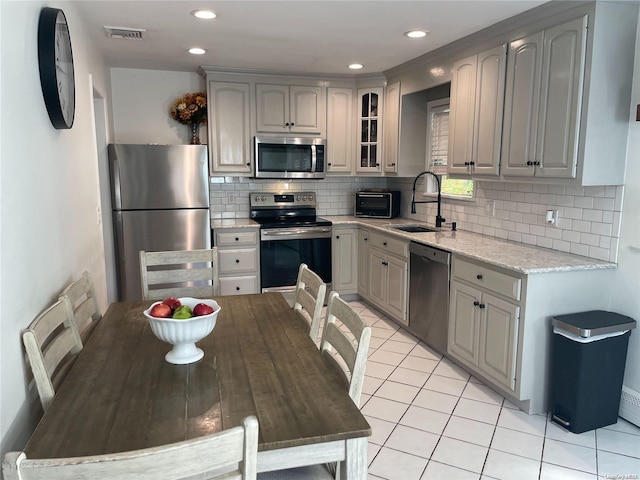 kitchen featuring gray cabinetry, decorative backsplash, sink, and appliances with stainless steel finishes