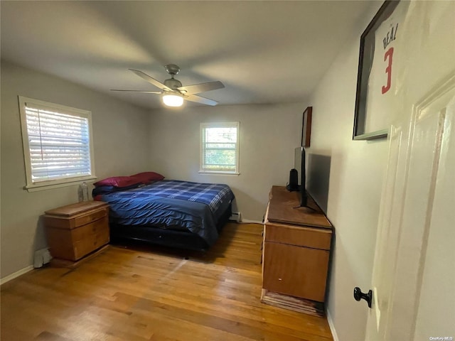 bedroom with a baseboard radiator, light hardwood / wood-style flooring, and ceiling fan