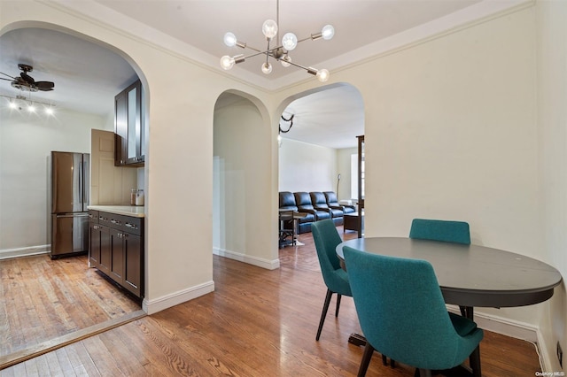 dining room featuring ceiling fan with notable chandelier, light hardwood / wood-style floors, and ornamental molding