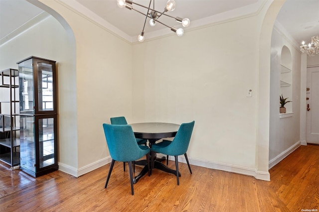 dining space featuring light hardwood / wood-style floors, crown molding, and an inviting chandelier