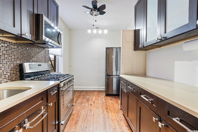 kitchen with light wood-type flooring, backsplash, dark brown cabinets, stainless steel appliances, and ceiling fan