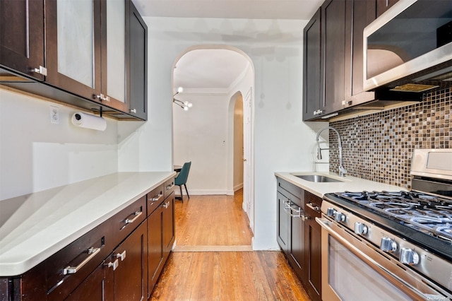 kitchen with sink, stainless steel appliances, dark brown cabinets, and light wood-type flooring