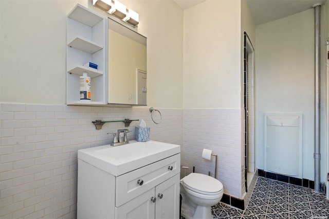 bathroom featuring tile patterned flooring, vanity, toilet, and tile walls