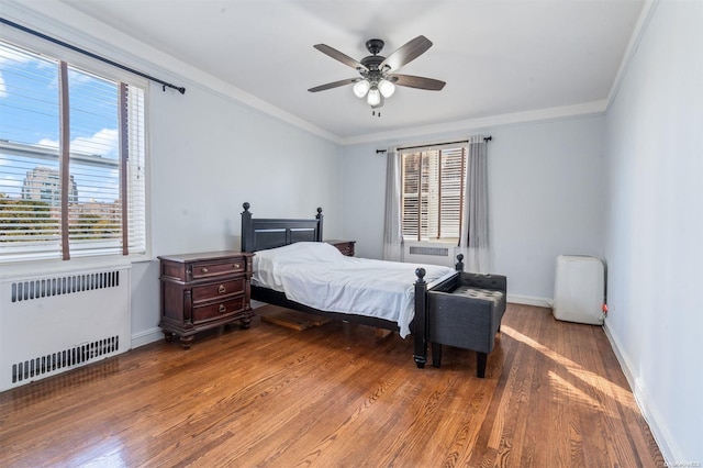 bedroom featuring wood-type flooring, radiator, crown molding, and ceiling fan