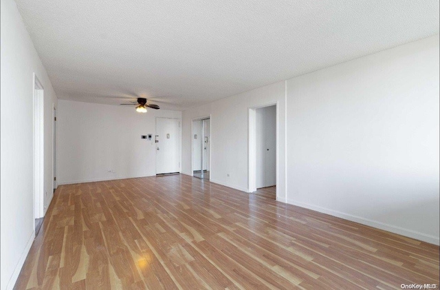 unfurnished room with a textured ceiling, light hardwood / wood-style floors, and ceiling fan