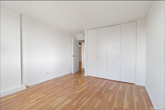 unfurnished bedroom with light hardwood / wood-style floors, a textured ceiling, and a closet