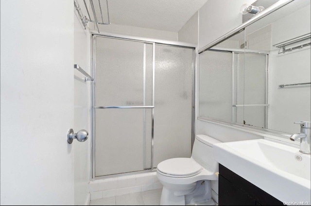 bathroom featuring vanity, tile patterned floors, toilet, a textured ceiling, and walk in shower