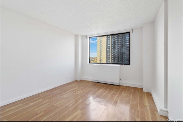 empty room with light hardwood / wood-style floors and a textured ceiling