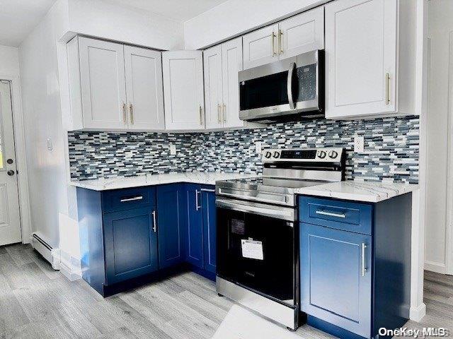 kitchen with blue cabinetry, tasteful backsplash, light hardwood / wood-style flooring, white cabinets, and appliances with stainless steel finishes