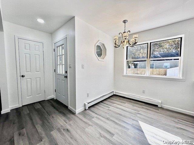 foyer entrance with a chandelier, wood-type flooring, and a baseboard radiator