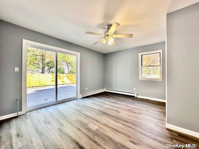 unfurnished room featuring hardwood / wood-style floors, ceiling fan, and a baseboard radiator