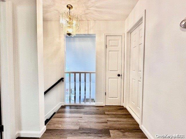 hallway with dark hardwood / wood-style flooring and an inviting chandelier