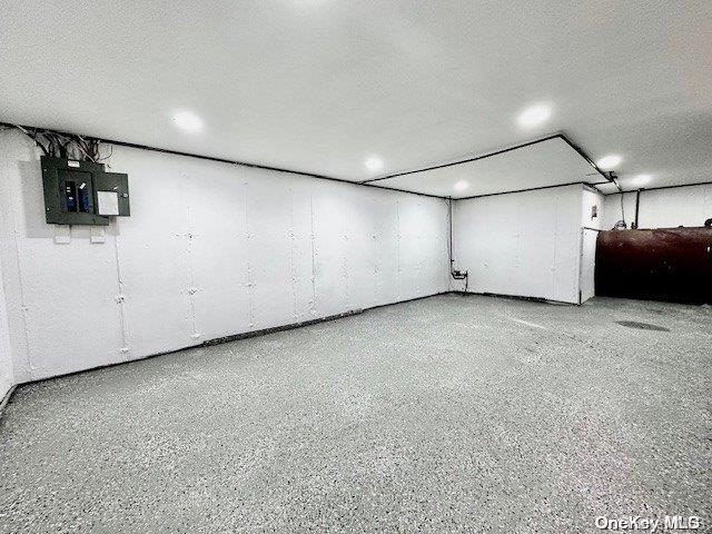 basement featuring a textured ceiling and electric panel