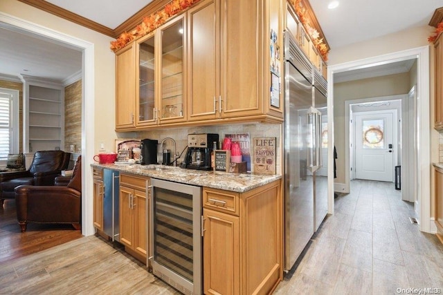 kitchen with light stone countertops, sink, beverage cooler, light hardwood / wood-style flooring, and ornamental molding