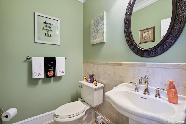 bathroom featuring toilet, crown molding, and sink