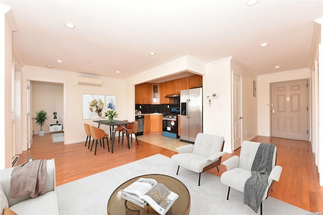 living room with a wall mounted AC, light hardwood / wood-style floors, and ornamental molding