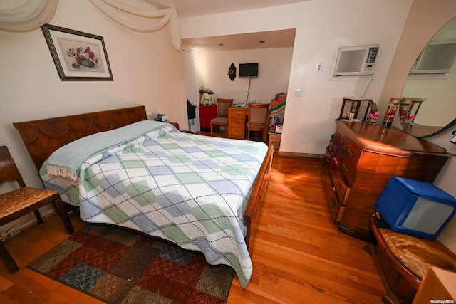 bedroom featuring a wall mounted air conditioner and hardwood / wood-style floors