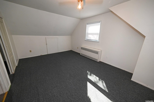 bonus room featuring dark colored carpet, vaulted ceiling, radiator, and ceiling fan