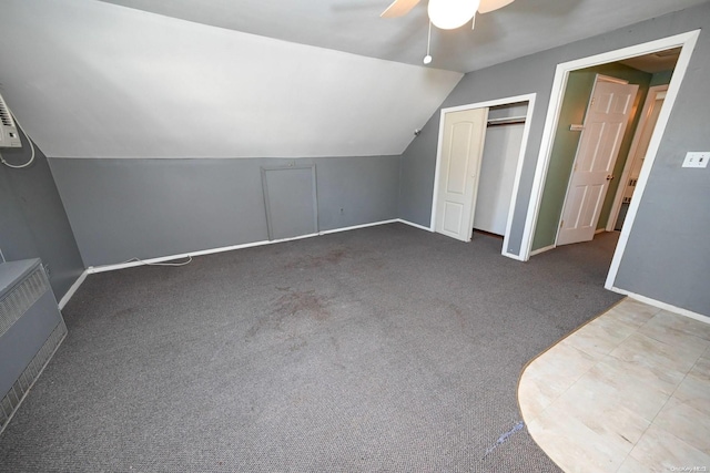 additional living space with ceiling fan, vaulted ceiling, and dark colored carpet