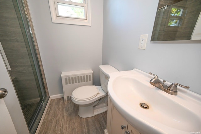 bathroom with radiator, vanity, a shower with door, wood-type flooring, and toilet