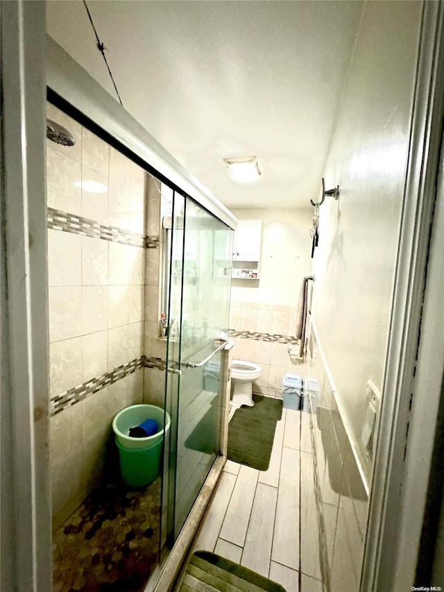 bathroom with toilet, tile walls, and walk in shower