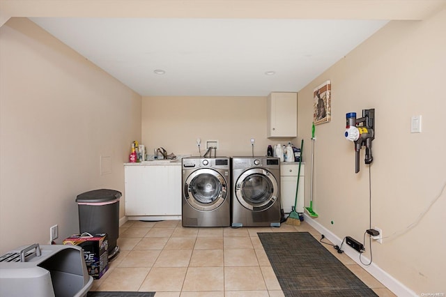 laundry area featuring cabinets, light tile patterned flooring, washing machine and dryer, and sink