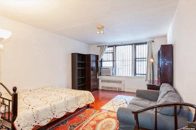 bedroom featuring radiator heating unit, cooling unit, and hardwood / wood-style floors