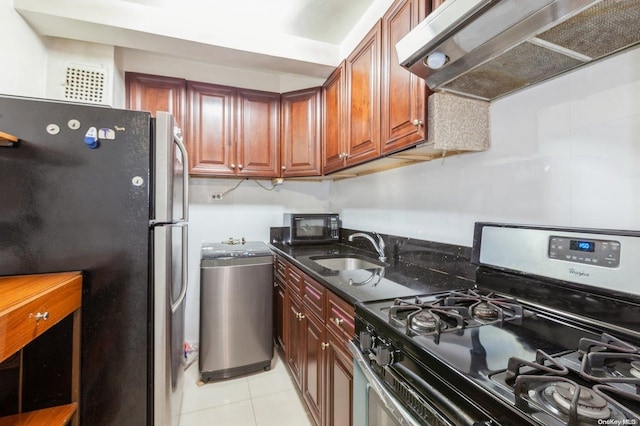 kitchen with sink, gas range, range hood, light tile patterned flooring, and stainless steel refrigerator