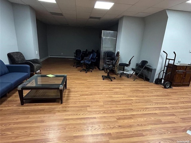 interior space featuring a paneled ceiling, light wood-type flooring, and a baseboard radiator