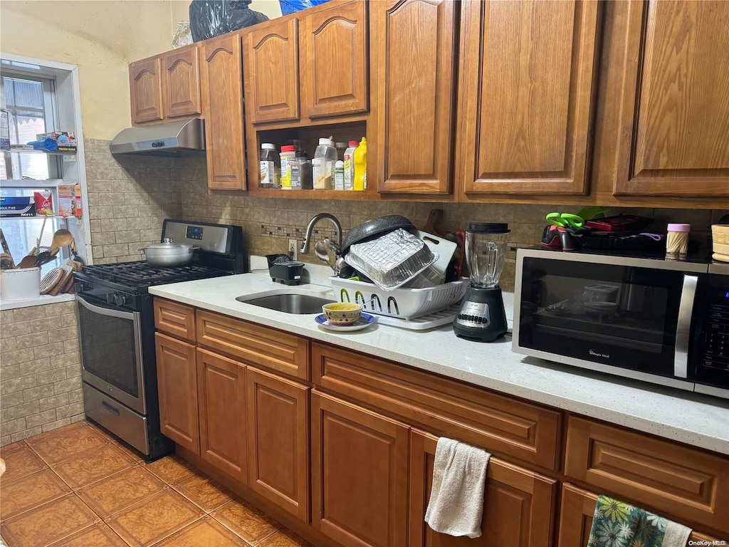 kitchen featuring sink, light tile patterned floors, appliances with stainless steel finishes, tasteful backsplash, and light stone counters