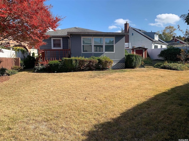 rear view of property featuring a storage shed and a yard