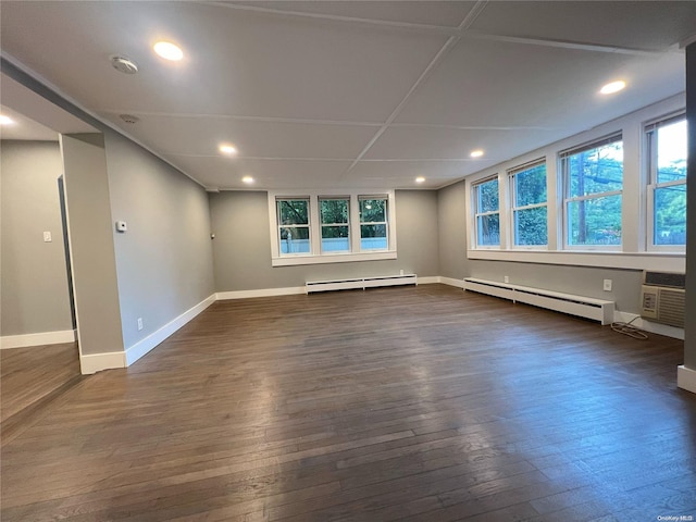 empty room with plenty of natural light, dark hardwood / wood-style flooring, and a baseboard heating unit