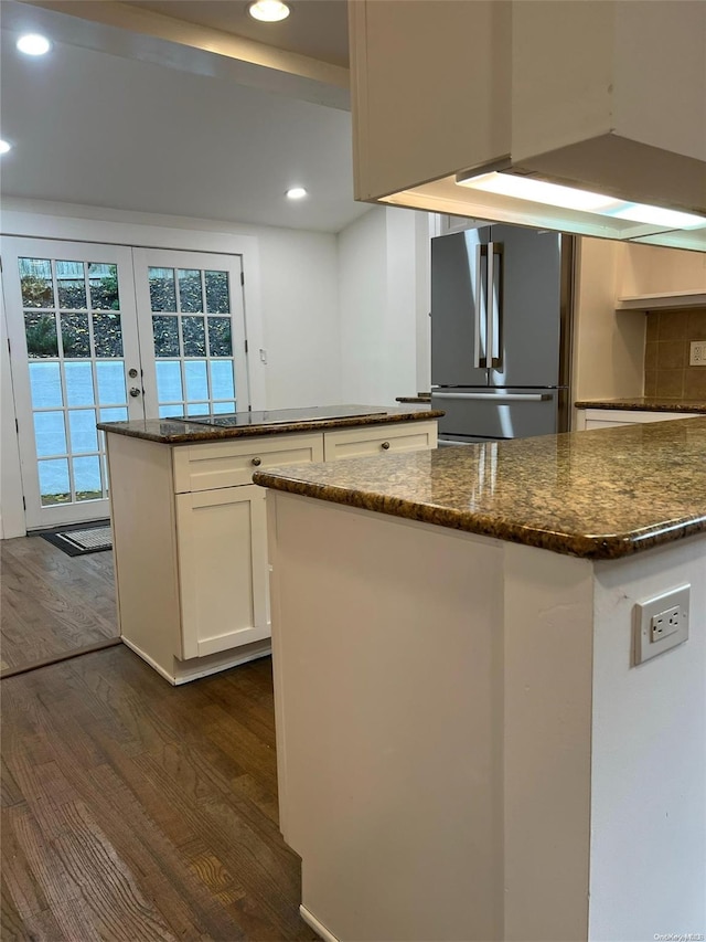 kitchen featuring white cabinets, dark wood-type flooring, stainless steel refrigerator, and a kitchen island