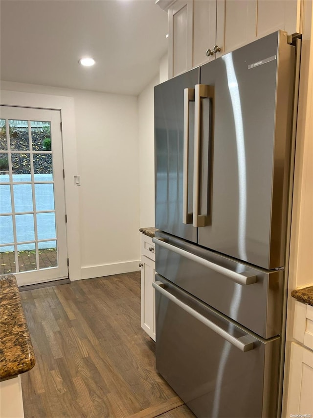 kitchen with white cabinetry, dark stone countertops, stainless steel fridge, and dark hardwood / wood-style floors