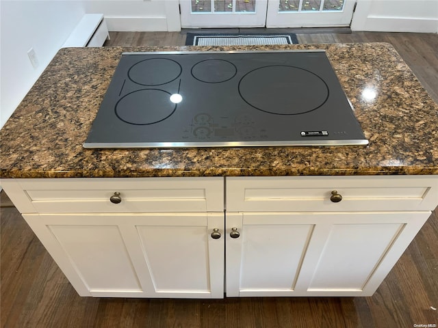 details with cooktop, dark hardwood / wood-style flooring, white cabinetry, and dark stone countertops