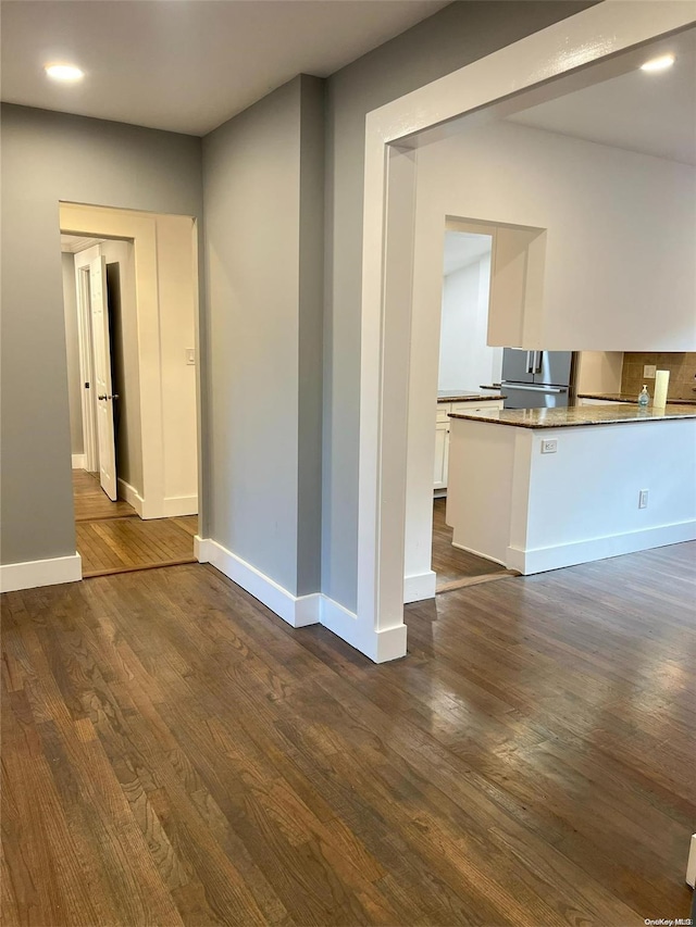 interior space featuring stainless steel fridge, white cabinets, and dark hardwood / wood-style floors